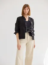 Chaqueta negra de lino y algodón, con corte recto, cuello mao, mangas 3/4 y bolsillos frontales. Presenta costuras a contratono en color ocre y cierre con botones de madera.