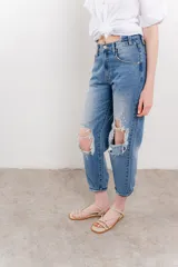 Jean azul de tiro medio y calce relaxed, con roturas amplias y desflecadas.