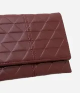 Billetera sobre color bordó con textura de triángulos en relieve y separadores internos para tarjetas y documentos.