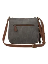 Cartera bandolera de tela estampada con motivos geométricos en tonos rosa, celeste, marrón y gris. Tiene un bolsillo frontal con cierre y un adorno de borla con cuentas de madera.