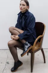 Bota de cuero vacuno con acabado charol, color marrón oscuro. Presenta un diseño de caña corta con cordones frontales y costuras decorativas en la puntera. La suela es de goma tipo crepe.