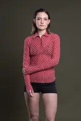 Polo de manga larga color rosa con estampado geométrico en blanco, cuello polo clásico y cierre parcial con cremallera.