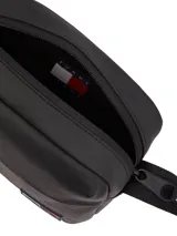 Bandolera negra de poliuretano con correa ajustable, cierre de cremallera, bolsillo exterior con cremallera, logo tonal de Tommy Jeans y parche engomado de Tommy en la parte delantera.