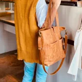 Bolso tipo tote bag color suela, de cuero, con doble asa de mano y correa larga extraíble y ajustable. Tiene dos bolsillos externos grandes.