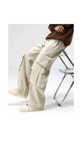 Pantalón cargo ancho de algodón gabardina color beige claro, con cintura elástica y regulable, y múltiples bolsillos cargo con pliegues en las piernas.