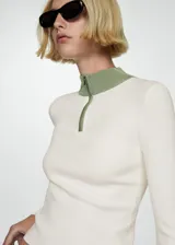 Jersey de punto fino color crudo, con cuello perkins verde y cierre de cremallera.