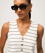 Chaleco sin mangas de punto, color blanco con rayas horizontales finas en negro. Presenta escote en V y cierre frontal con botones marrones.