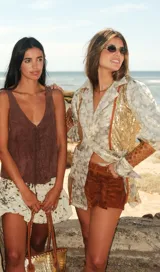 Blazer de corte recto confeccionado en brocado con diseño floral y paneles laterales de lentejuelas doradas. Presenta mangas con volumen en la parte superior, detalles de calados geométricos en los antebrazos y puños con lazos. Incluye recortes decorativos en contraste y cierre frontal con botón.