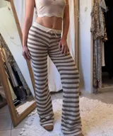 Conjunto de dos piezas tejido a crochet, compuesto por un top halter y un pantalón acampanado. El tejido es calado con rayas horizontales en tonos beige claro y marrón.