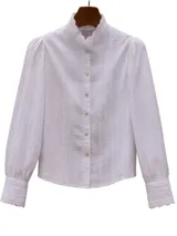 Blusa blanca con cuello alto con volados, mangas largas abullonadas con puños con volados y bordado inglés.