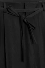 Pantalón negro de tiro alto, corte ancho y largo midi. Incluye bolsillos delanteros, pinzas y cinturón de la misma tela.