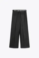 Pantalón negro de tiro alto con pinzas delanteras, pernera ancha y cinturón de cuero con hebilla dorada.