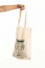 Bolso tipo totebag de tela color crudo con estampa de una casa en color rojo.