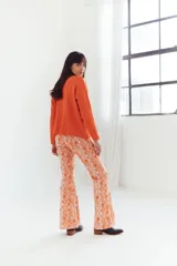 Pantalón de corte acampanado con estampado geométrico en tonos naranja, rosa y blanco.