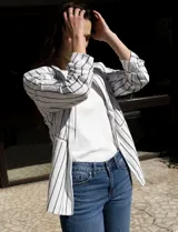 Blazer blanco con rayas verticales negras, cuello con solapa, bolsillos simulados y mangas 3/4 fruncidas. Forro interno blanco, marca Dictionary.