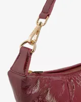 Bolso tipo baguette color borgoña de cuero brillante, con correa de hombro extraíble y herrajes dorados.