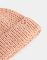 Gorro de lana tejido color rosa viejo, con pompón en la parte superior y etiqueta metálica con logo en el borde.
