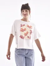 Remera blanca con estampado de flores en colores cálidos, corte recto y mangas cortas.