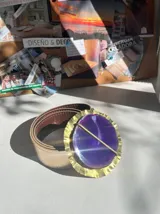 Cinturón dorado con hebilla texturada y piedra ágata en tonos violeta.