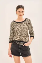 Sweater de viscosa con estampado animal print de leopardo, mangas 3/4, cuello redondo y calce al cuerpo. Tiene guardas a contratono en puños, cuello y ruedo, e hilados de lurex.