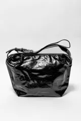 Bandolera negra de cuero sintético con correa de hombro ajustable y cierre superior con cremallera.