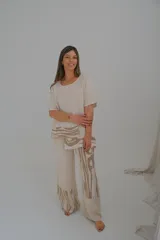 Pantalón de lino color beige con estampado abstracto en tonos marrones en la parte inferior de las piernas.