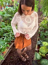 Buzo tejido color crudo con mangas largas y calado en el frente.