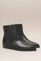 Bota corta de cuero vacuno color negro, con punta fina y taco bajo.
