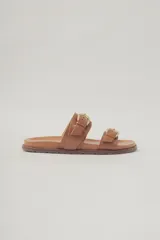 Sandalias planas de cuero color marrón claro, con dos tiras anchas sobre el empeine, ajustables con hebillas metálicas doradas.