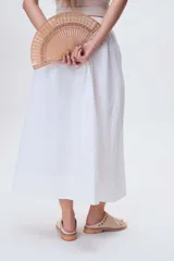 Sandalias bajas de cuero color beige con detalle de tachas metálicas en la tira delantera.