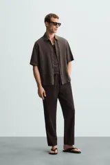 Pantalón de corte relajado (relaxed fit) color verde militar, confeccionado en mezcla de algodón y lino. Presenta cintura elástica ajustable con cordón y bolsillos frontales y traseros de vivo.