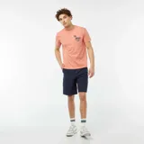 Remera color salmón de manga corta con cuello redondo y estampado pequeño en el pecho con una palmera y texto en azul.