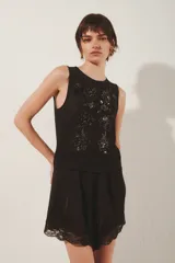 Top negro sin mangas confeccionado en mesh con bordado de flores a tono.