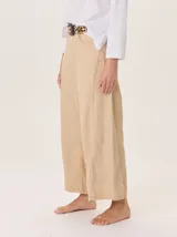 Pantalón ancho color beige claro, con corte holgado y costuras visibles en el frente de cada pierna.