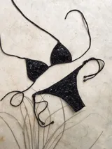 Conjunto de bikini con corpiño de triángulos movibles con tiras finas para atar al cuello y a la espalda. Incluye bombacha vedetina con tiras finas a los costados para atar.