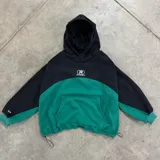 Buzo crop de frisa negro y verde con capucha, bolsillo frontal, estampa en el frente, etiqueta bordada en el puño derecho y ajuste con tancas en la cintura. Fabricado en Uruguay por Rufián Co.