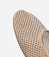 Zapatilla tipo bailarina color beige, con capellada de red calada, puntera redonda y tira de charol con hebilla en el tobillo.