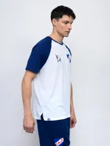 Remera blanca con mangas raglán azul marino, cuello redondo y logo del Club Nacional de Football estampado en el pecho.