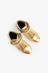 Zapatillas de caña alta doradas, con cordones y tira de velcro en el tobillo.