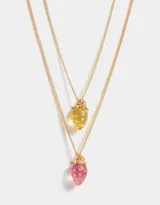 Set de dos collares dorados con dije de frutilla transparente con glitter, uno rosado y otro amarillo.