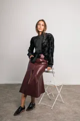 Camisa negra de terciopelo con motivos florales, cuello mao, mangas abullonadas, detalles plisados en el frente, botones forrados y bordes con puntilla.