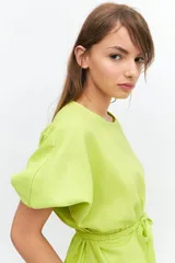 Blusa color verde lima, de manga tres cuartos con leve volumen y largo hasta la cadera. Incluye cinto extraíble en espalda que permite anudar para modificar la silueta.