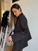 Blazer negro de corte recto, con solapas de muesca y cierre cruzado con doble botón.