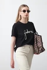 Remera de manga corta color negro con cuello redondo y estampado frontal en blanco con la palabra "j'adore" en tipografía cursiva.