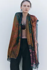 Pañuelo rectangular de modal con estampado floral en tonos ocre, rosa y verde. Tiene terminaciones deshilachadas.