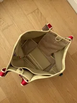 Bolso negro tipo tote de neopreno con bolsillo interno de red, sobre haciendo juego y gancho para sujetarlo.