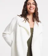 Cardigan alargado color blanco, con cuello virada, forro de pelos y confeccionado en punto pesado. No tiene cierre.