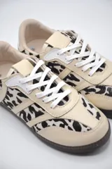 Zapatilla de cuero beige con estampado animal print, detalles en blanco y suela de goma caramelo.