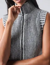 Chaleco tejido de punto con cuello alto y cierre frontal con cremallera, con diseño a rayas verticales en blanco y negro.