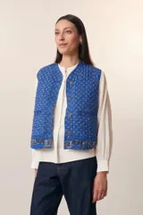 Chaleco acolchado azul con estampado floral, cuello redondo y cierre frontal con botones de madera.
